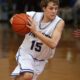 Teen male basketball player in action on indoor court during a game.