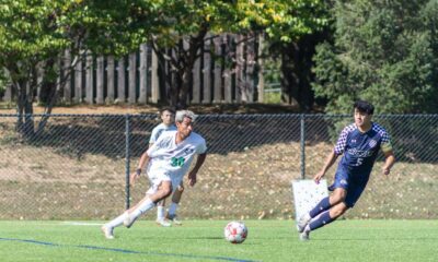 Players in action during a competitive outdoor soccer match on a sunny day.
