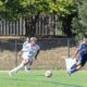 Players in action during a competitive outdoor soccer match on a sunny day.