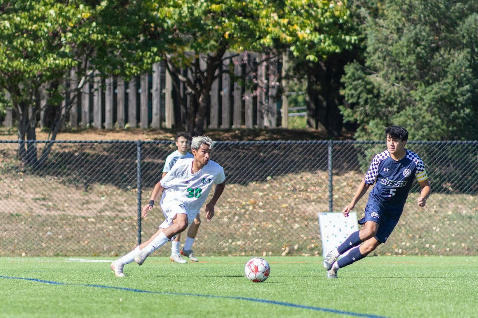 Players in action during a competitive outdoor soccer match on a sunny day.
