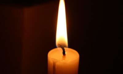 A glowing candle casting a warm light in a dark room, creating a serene atmosphere.