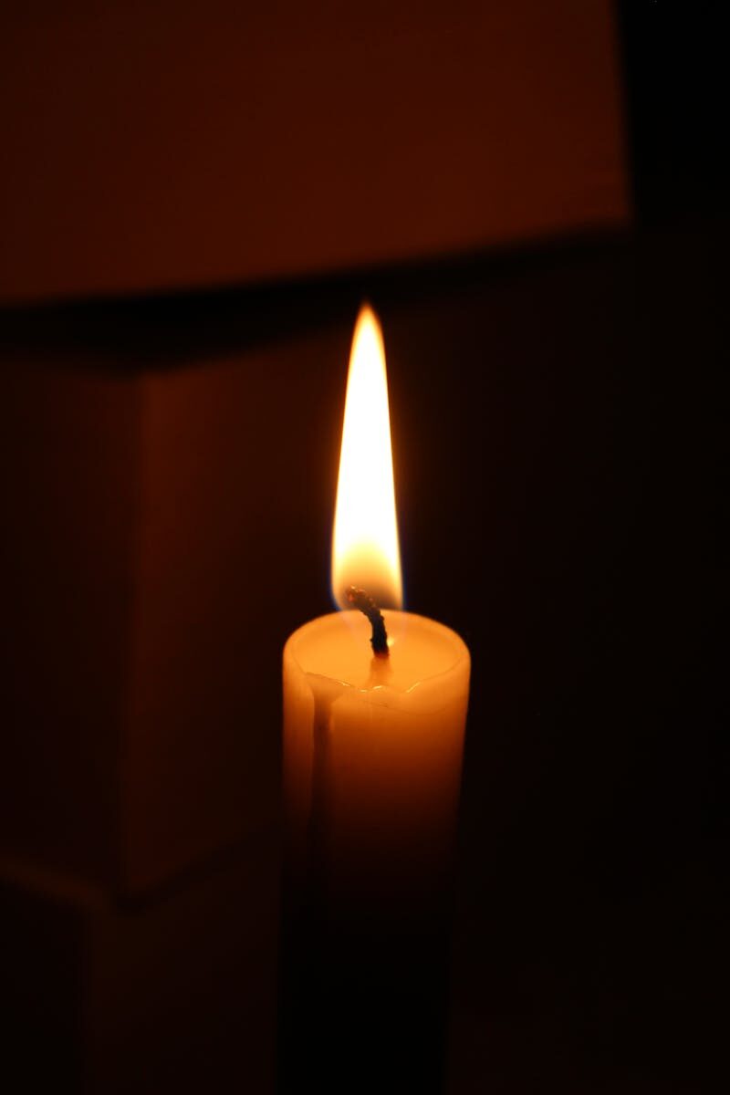 A glowing candle casting a warm light in a dark room, creating a serene atmosphere.