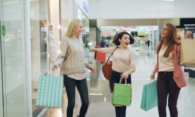 Three women with shopping bags in a mall.