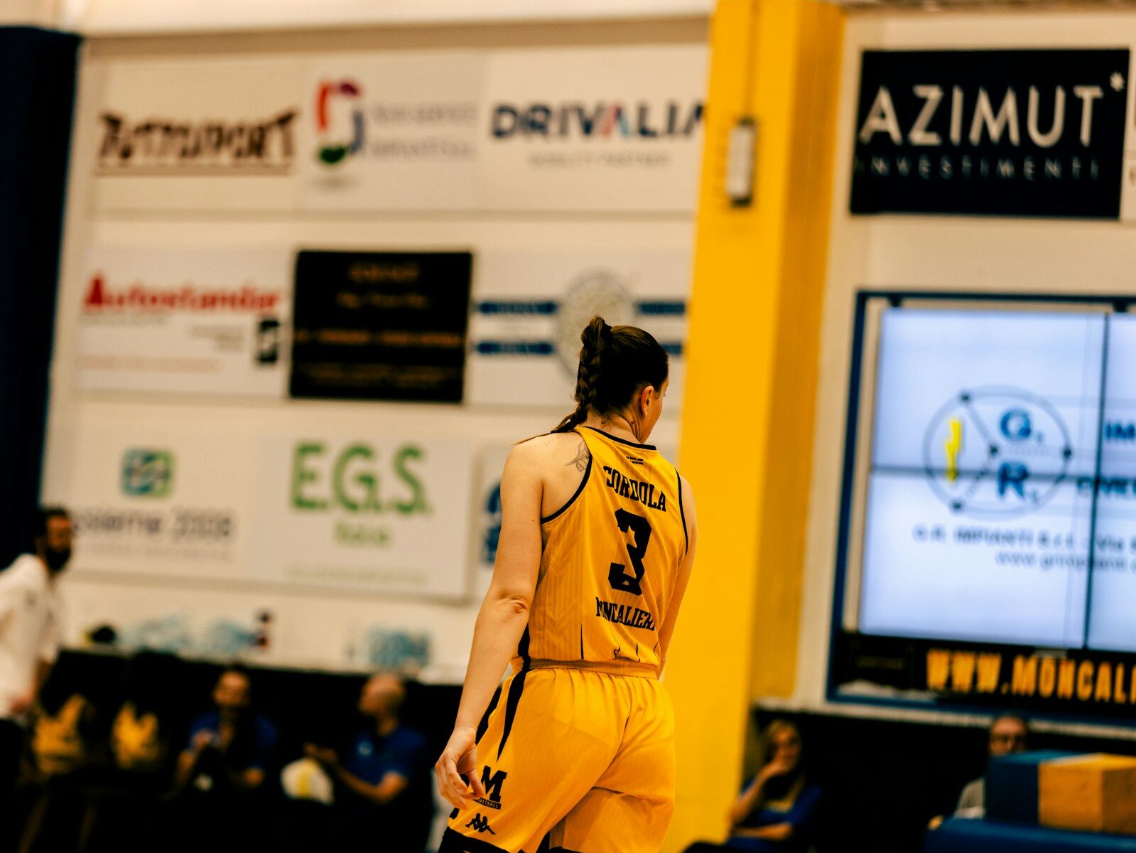 A man in a yellow uniform standing on a basketball court