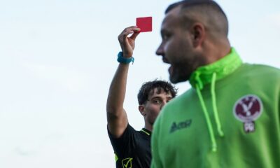 A man in a green hoodie holding up a red card