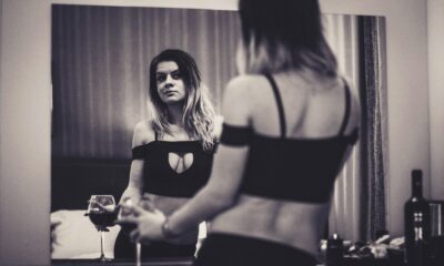 a woman standing in front of a mirror holding a wine glass