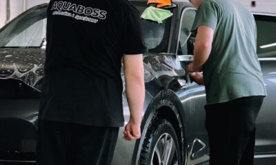 Two men detailing a car in an indoor workshop, focusing on precision and care.