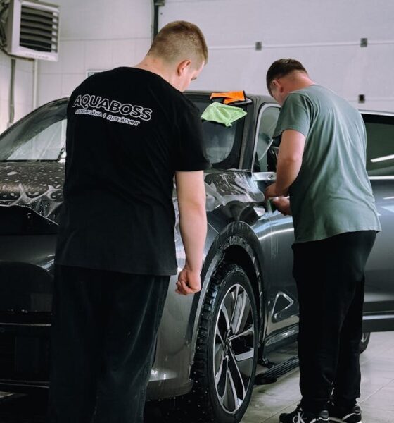 Two men detailing a car in an indoor workshop, focusing on precision and care.