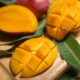 Close-up of ripe mango slices on a wooden board with leaves. Perfect for tropical fruit themes.