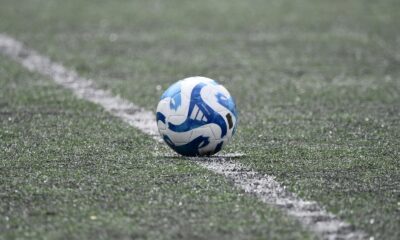 Close-up of a blue and white soccer ball resting on a lined green turf field.