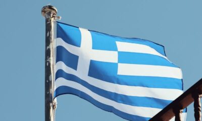 The Greek flag waves on a clear day in Naxos, Greece, showcasing Aegean architecture.