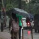 Person walking on a wet street under an umbrella during a rainy day, capturing urban life.