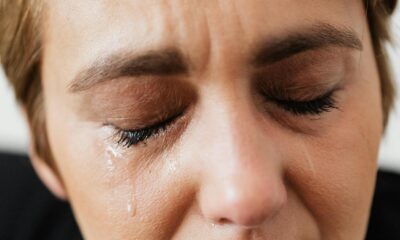 Closeup of crop unrecognizable middle aged woman suffering from depression and crying with closed eyes