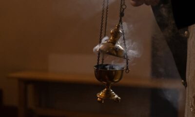 A close-up of an orthodox censer with smoke rising in a dimly lit indoor setting.