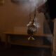 A close-up of an orthodox censer with smoke rising in a dimly lit indoor setting.
