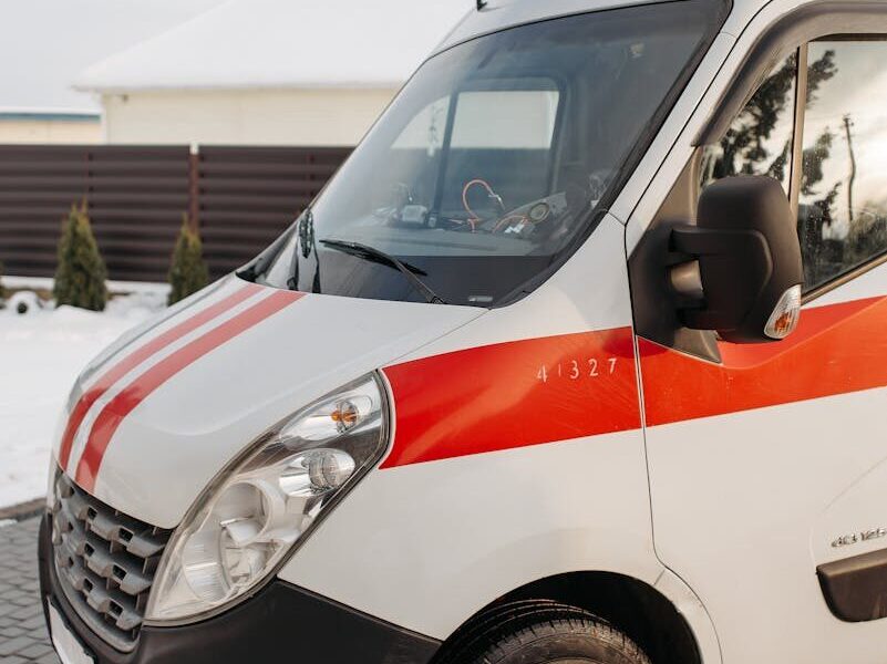 Close-up of a red and white ambulance vehicle parked outdoors during the day.