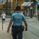 A police officer walking down a city street during the day, maintaining law and order.
