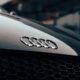 Detailed close-up of a black luxury car's iconic logo and sleek design.