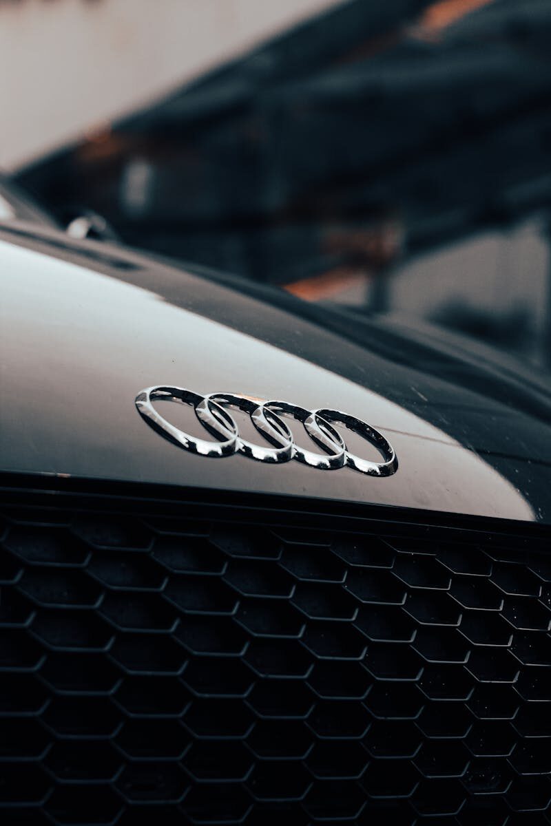Detailed close-up of a black luxury car's iconic logo and sleek design.