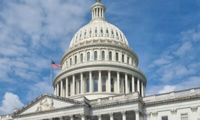 A striking view of the US Capitol dome with flag and blue sky in Washington, DC.