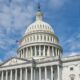 A striking view of the US Capitol dome with flag and blue sky in Washington, DC.