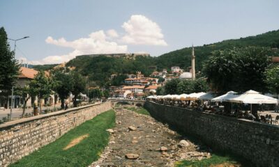 Panoramic view of Prizren's charming riverside cafes and historic architecture on a sunny day.
