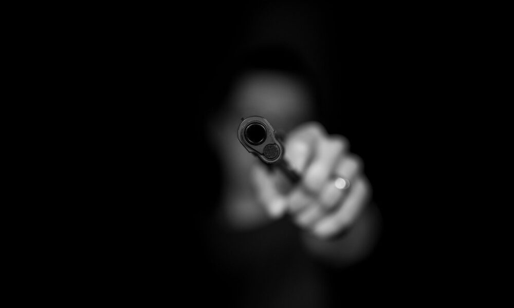 grayscale photography ofperson holding gun