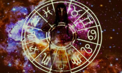 Woman standing with astrological symbols projected, evoking a mystical vibe.