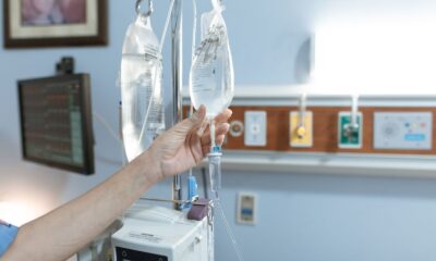 Close-up image of an IV drip and hand in a hospital room, illustrating medical care.
