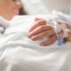 Focused shot of a patient's hand with IV in a hospital setting.