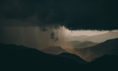 A breathtaking view of mountainous hills beneath dramatic storm clouds at sunset.