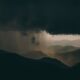 A breathtaking view of mountainous hills beneath dramatic storm clouds at sunset.