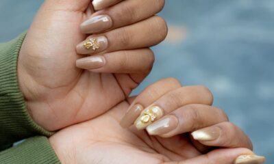 Close-up of hands showcasing artistic manicure with gold leaf details on a natural skin tone.