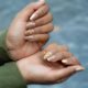 Close-up of hands showcasing artistic manicure with gold leaf details on a natural skin tone.