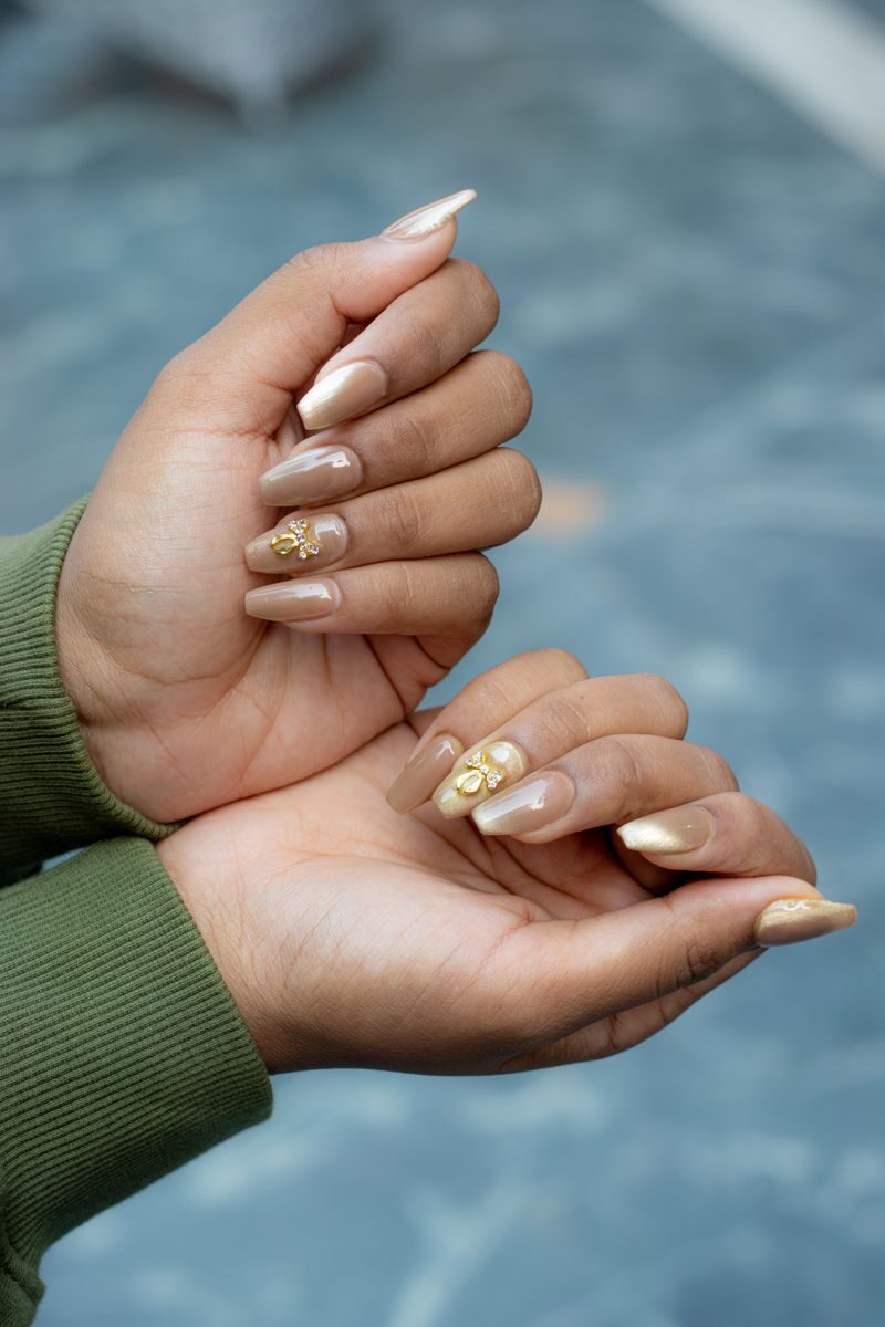 Close-up of hands showcasing artistic manicure with gold leaf details on a natural skin tone.