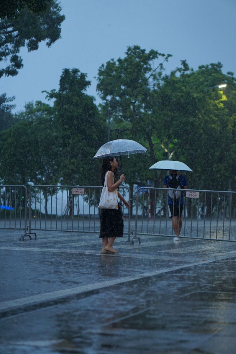A woman walking with an umbrella during a rainy day, capturing mood and motion.