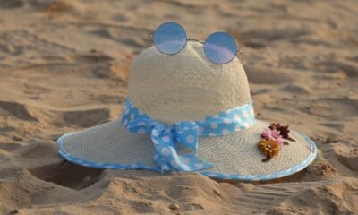 Charming straw hat adorned with flowers and sunglasses on a sunny beach day.