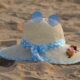 Charming straw hat adorned with flowers and sunglasses on a sunny beach day.
