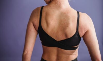 Back view of crop anonymous female in black sportive underwear standing against purple background in studio