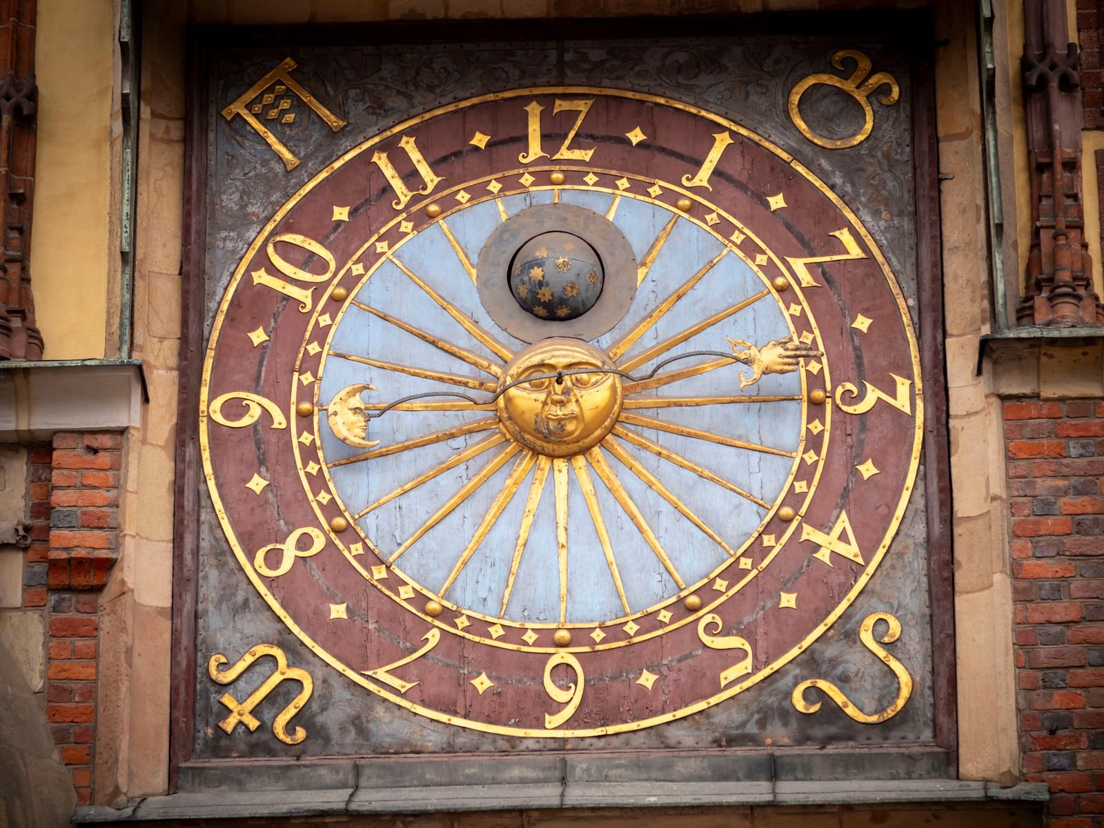 Close-up of a historic astronomical clock on a building facade in Poland.