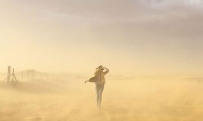 A woman braves a windy desert in Utah, creating a picturesque scene with dust and soft light.
