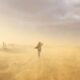 A woman braves a windy desert in Utah, creating a picturesque scene with dust and soft light.