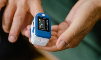 Hands of an adult using a pulse oximeter device to measure oxygen levels indoors.