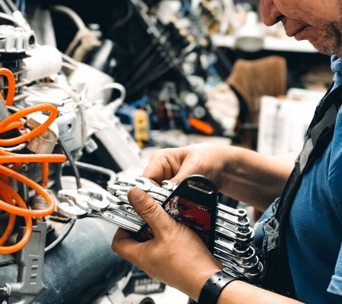 Experienced male technician working on complex machinery in workshop.