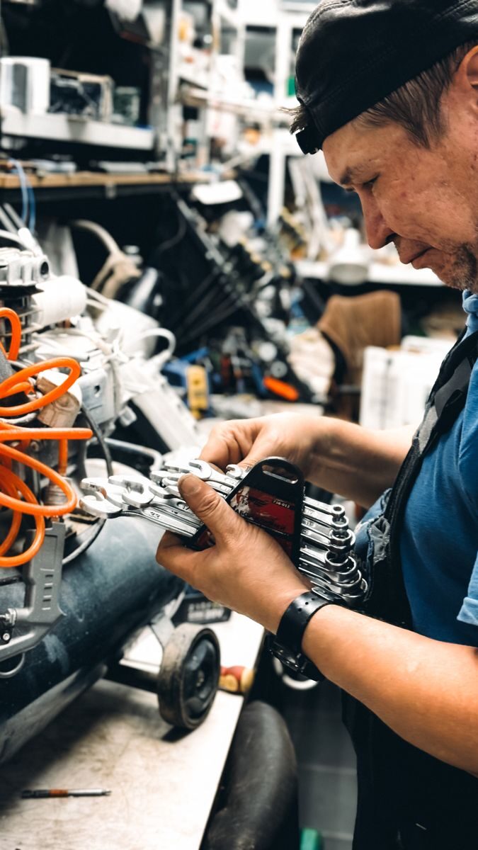 Experienced male technician working on complex machinery in workshop.