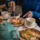 Woman enjoying breakfast with poached eggs, toast, and tea in a cozy setting.