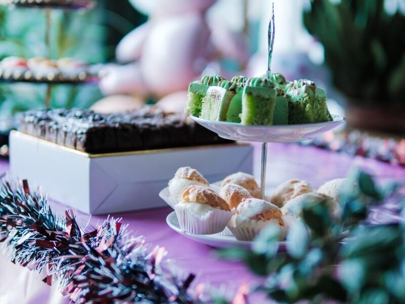 Vibrant party table setup with colorful cakes, pastries, and decorations in a festive setting.