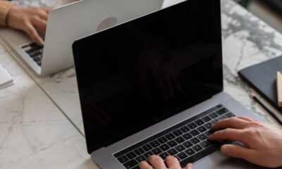 Two people working on laptops in a modern office setting, showcasing teamwork and productivity.