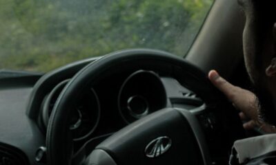 Close-up of a man driving a car, focusing on the steering wheel and interior setup.