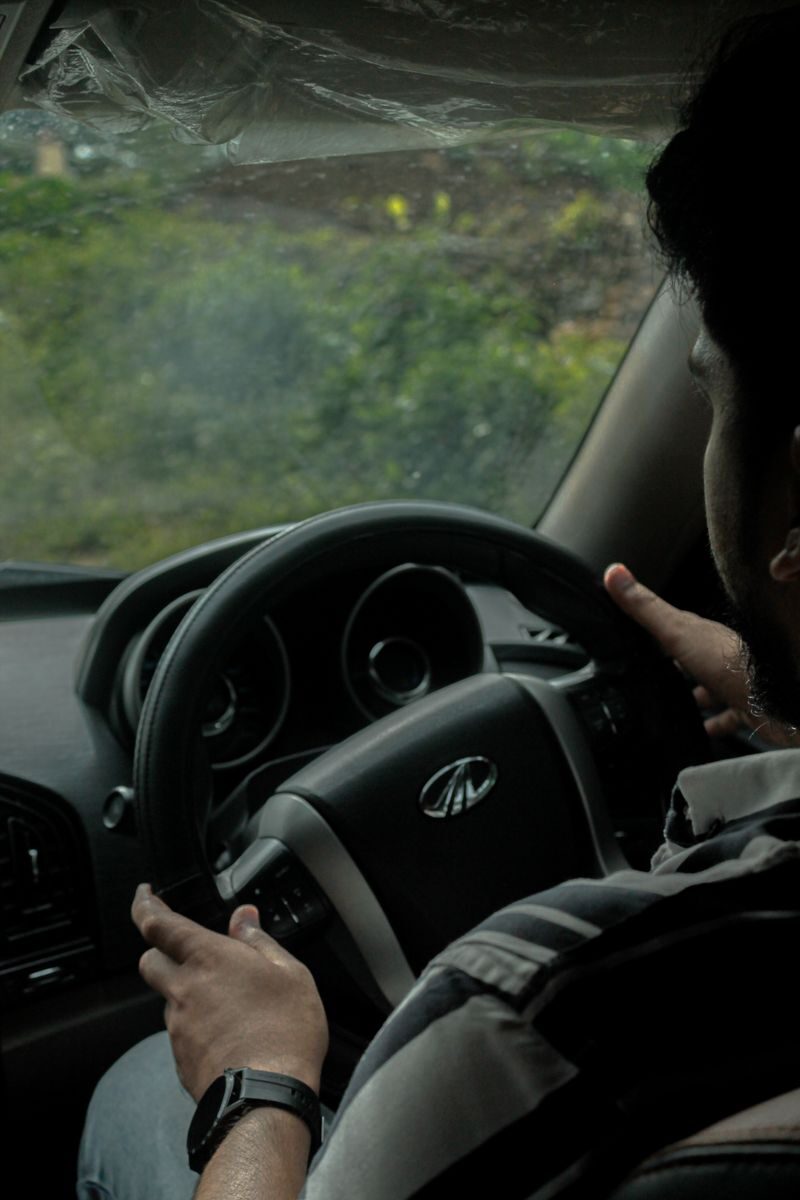 Close-up of a man driving a car, focusing on the steering wheel and interior setup.
